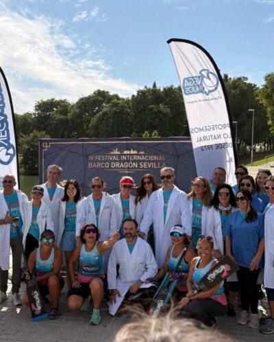 Participantes y profesionales sanitarios posan con batas y palas durante la jornada de barco dragón en Sevilla
